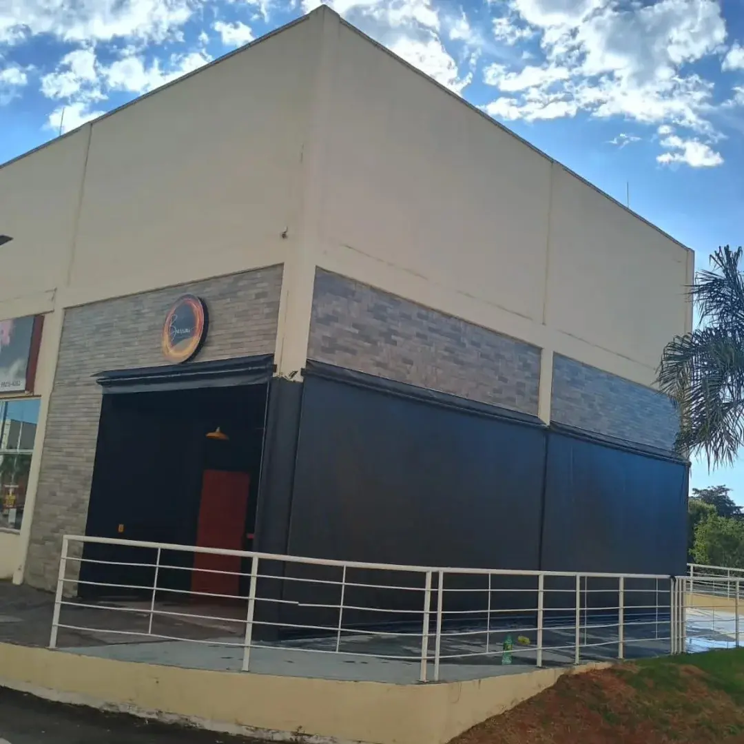 Fachada comercial com toldos escuros nas laterais e entrada aberta