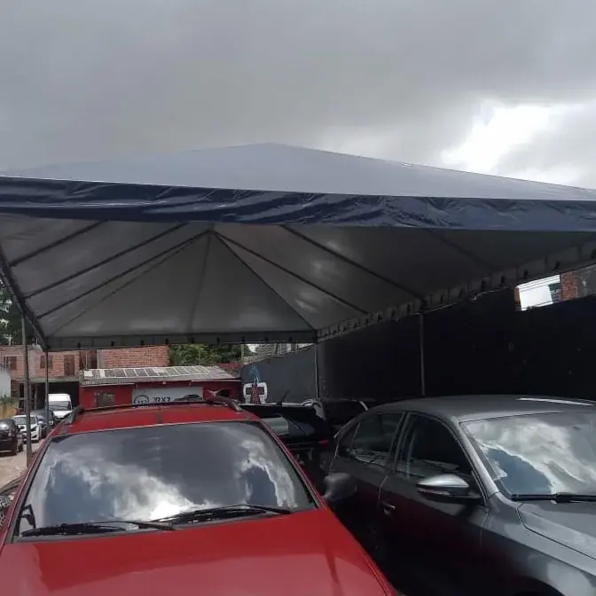 Cobertura de lona branca com borda azul sobre carros estacionados