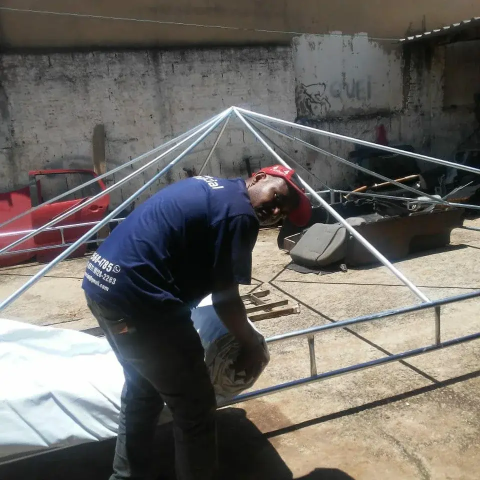 Profissional da Manancial montando a estrutura de uma tenda piramidal na oficina